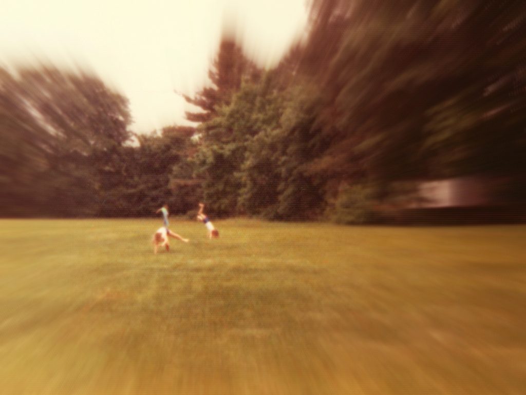 blurry photo of two children cartwheeling in the grass